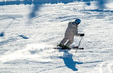 Close up of a downhill skier speeding down a mountain with a trail of snow. Stock Photos