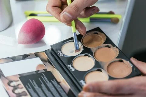 Close-up of a drag queen's hands applying foundation from a palette Stock Photos