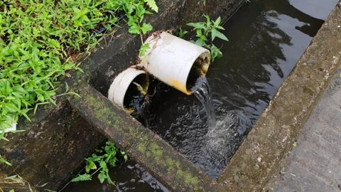 A close-up of a drainpipe that drains clear water out into a sewer Stock Footage 304050651