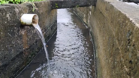 A close-up of a drainpipe that drains clear water out into a sewer Stock Footage 304050766