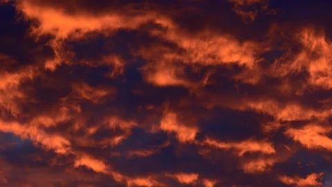 Close-up of dramatic twilight sky with glowing fiery red and dark orange clouds Stock Photos