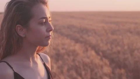 Close-up dramatic view of young woman's face in sunset light on the golden wheat Stock Footage 200880658