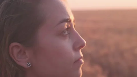 Close-up dramatic view of young woman's face in sunset light on the golden wheat Stock Footage 200880906