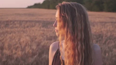 Close-up dramatic view of young woman's face in sunset light on the golden wheat Stock Footage 200905536