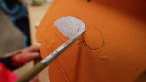Close-up of drawing the bird with hand and gray paint on orange plywood craft Stock Footage 232637842