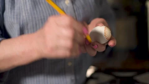 Close up drawing patterns with wax with a pencil on an egg near a stove by woman Stock Footage 131016031