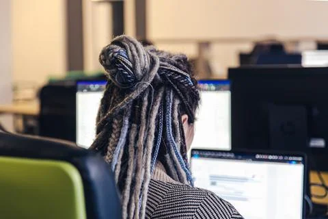 Close-up of dreadlocks of a girl working at the computer, back view. Foto stock
