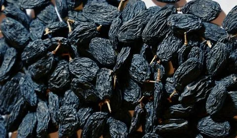 Close-up of dried dark blue raisins with stems piled together Stock Photos