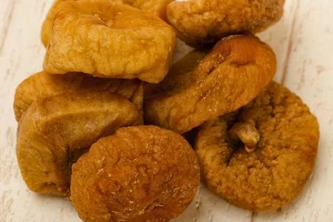 Close up of dried figs piled on a light wooden surface Stock Photos