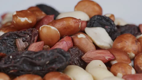 A close up of dried fruit and nuts on a white plate - slowly rotates. 4K tripod Stock Footage 169120086