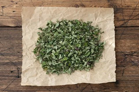Close-up of dried oregano on crumpled brown paper with a rustic wooden table Stock Photos