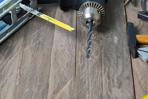 Close up of a drill bit and utility knife on a wooden surface Stock Photos