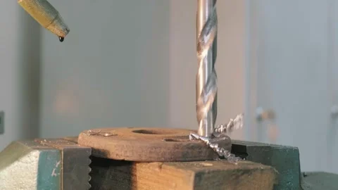 Close-up of a drill bit carving a hole into a metal part clamped down. Stock Footage 150755044