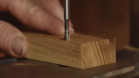 Close up on drill bit drilling a hole through hard hedge wood as man holds Video stock 107670638