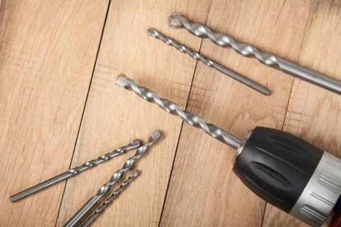 Close up drilling machine, screwdriver with drills on wooden table . Prepared Stock Photos