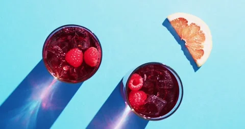 Close up of drinks with raspberries and grapefruit over blue background Stock Footage 331447577