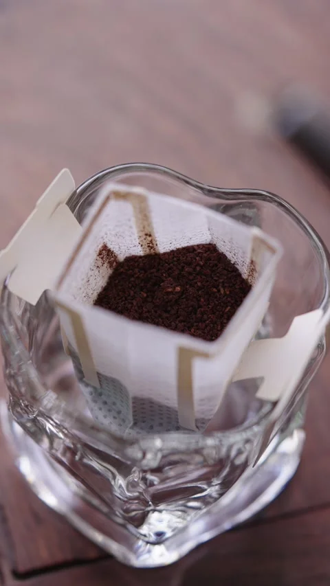 Close-up of the drip filtering process of brewing hanging coffee with hot water Stock Footage 340193663