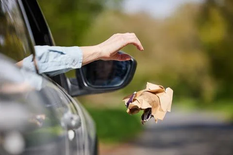 Close Up Of Driver In Car Dropping Trash Out Of Window On Country Road Stock Photos