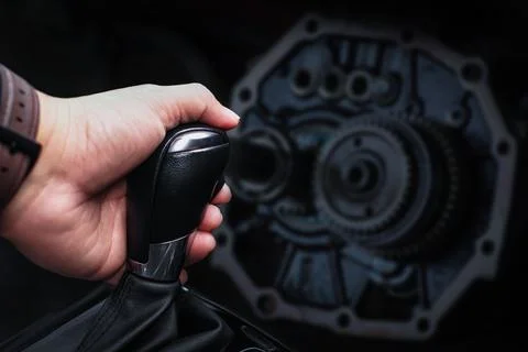 Close up of driver hand changing gears with metal gears blurred on background Stock Photos