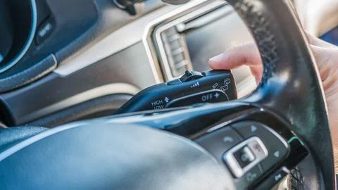 Close up driver hand using windshield wiper lever inside vehicle Stock Photos