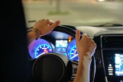 Close up of driver hands holding steering wheel driving car with blurred city Stock Photos