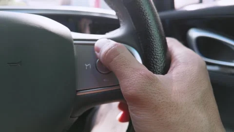 Close-up of a driver using steering wheel controls inside a modern car. 스톡 동영상 344088706
