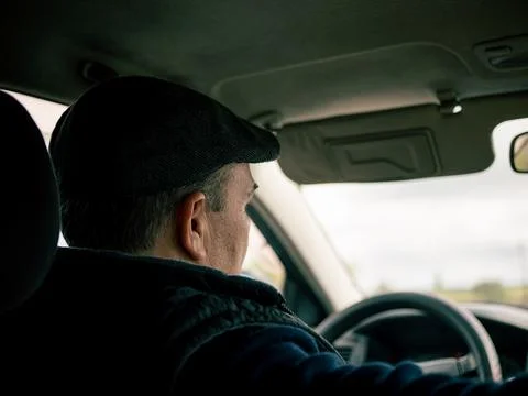 Close-up of a driver wearing a dark flat cap Foto stock