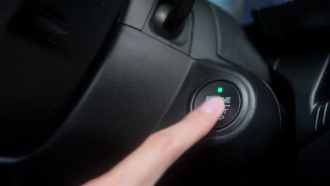 Close-up of a driver's finger about to push a car's engine start stop button Stock Footage 345330344