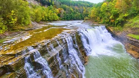 Up close with drone to beautiful waterfall eroding cliffs with colorful forests Foto stock