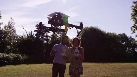 Close Drone In Foreground With Man and Woman Pilots Behind It In Slow Motion Stock Footage 82584766
