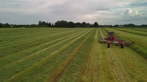 Close-Up Drone Shot Following a Tractor Pulling a Hay Tedder Stock Footage 345012734