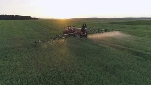Close up drone shot of tractor spraying green field in the evening Stock Footage 133999209