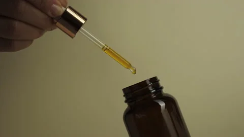 Close-up of a drop of oil dripping into a bottle. Stock Footage 144016912