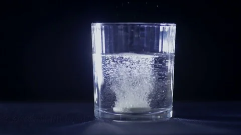 Close-up of dropping a round white tablet into a glass of water 動画素材 75547036