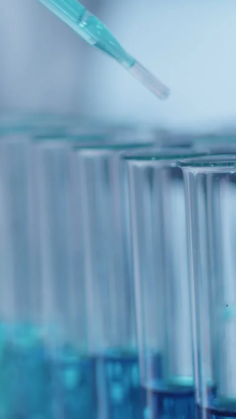 Close-up of Drops of Blue Solution Falling from Pipette into Test Tubes Video stock 299689157