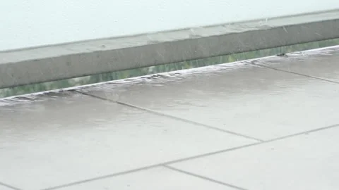 Close-up of drops fall on the wet grass floor of a balcony. Raindrops falling Vidéo 290463517