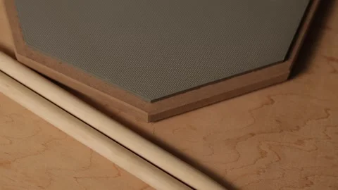 Close-up of drumsticks resting on a practice pad with wood grain background Vidéo 341737478