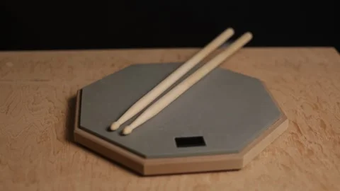 Close-up of drumsticks resting on a practice pad with a wooden background Vidéo 341737534