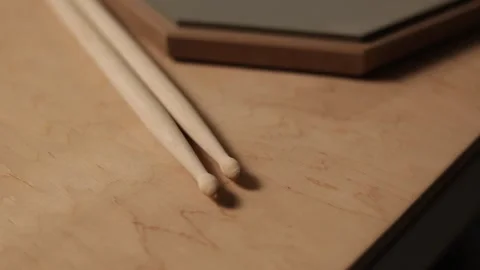 Close-up of drumsticks resting on a wooden surface with a practice pad Vidéo 341737518