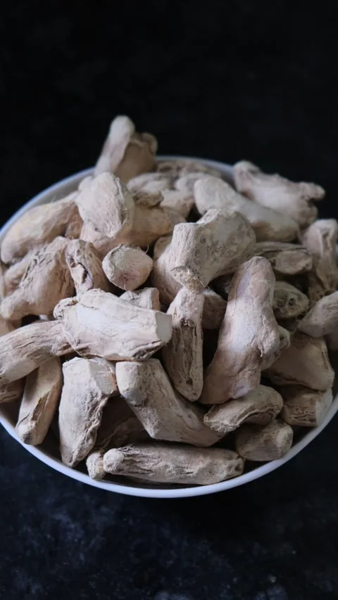 Close up of dry ginger roots in white bowl on dark background 库存影片 331987530