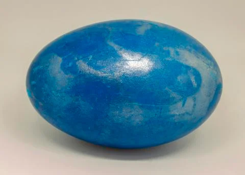 Close-up of a duck egg colored in blue with pearl glitter. Stock Photos