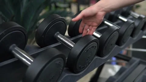 Close-Up of Dumbbell Rack being used in Fitness Center Wide Range of Weight Stock Footage 256750502