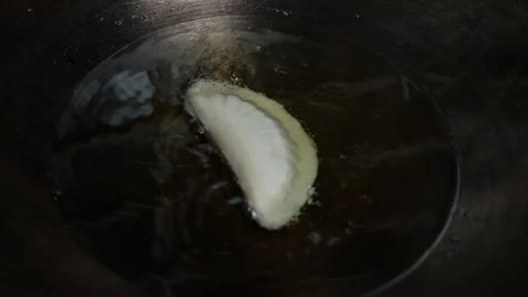 Close-up of a dumpling frying in hot oil in a dark pan, with bubbles around.. Stock Footage 339022836