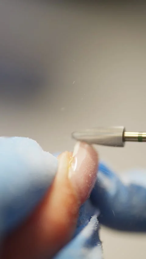 Close-up of dust flying while removing gel with a manicure machine. Video stock 343537993