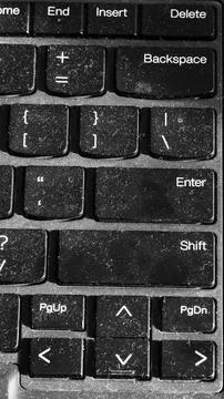 Close-up of a dusty black computer keyboard showing wear from frequent use Stock Photos