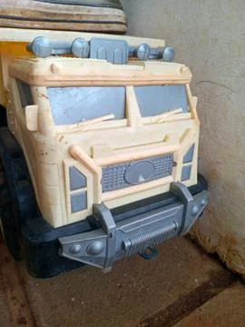 Close up of dusty plastic toy dump truck front cab in beige and gray, indoo.. Stock Photos