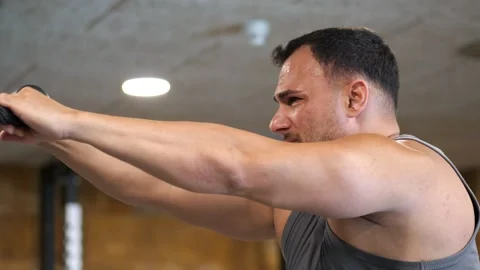 Close-up dynamic shot of an athletic man intensely straining during cable r.. Vidéo 344031815
