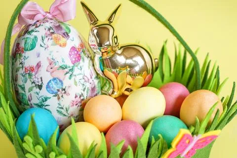 Close-up of an Easter Basket with Colorful Eggs and a Golden Bunny Foto stock