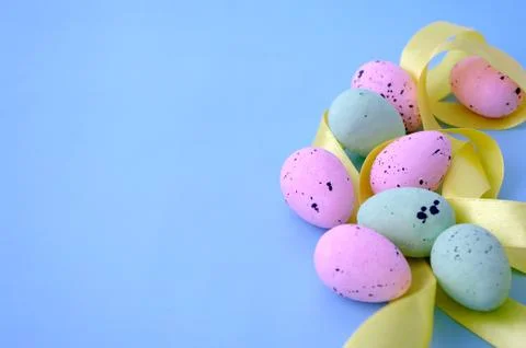 Close up easter composition, pink green quail eggs with yellow ribbon on pastel Foto stock