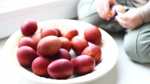 Close-up Easter eggs on the plate. Color red eggs and kid's hands touching and Stock Footage 238857556